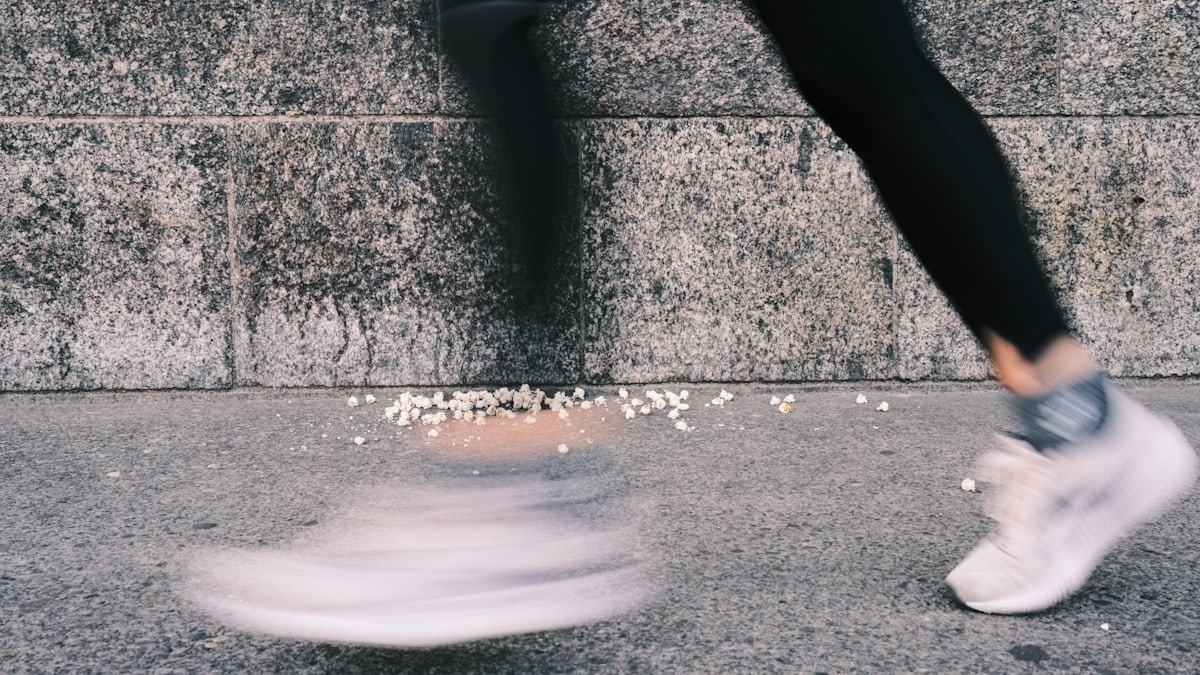 a person walking on a sidewalk near a wall